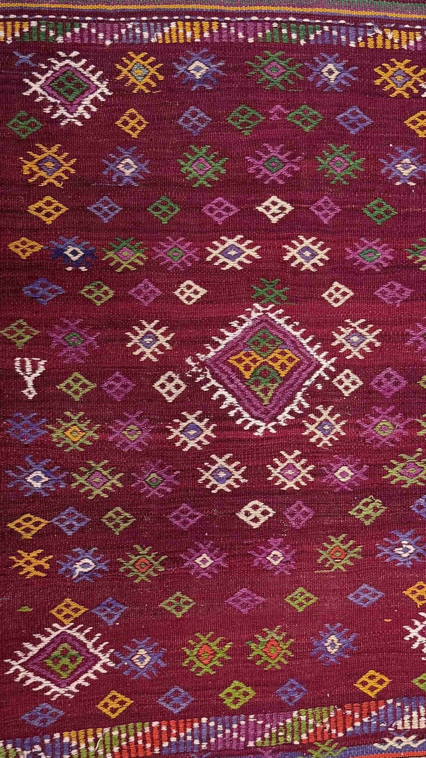 Colorful patterned wool kelim with geometric designs on a red background