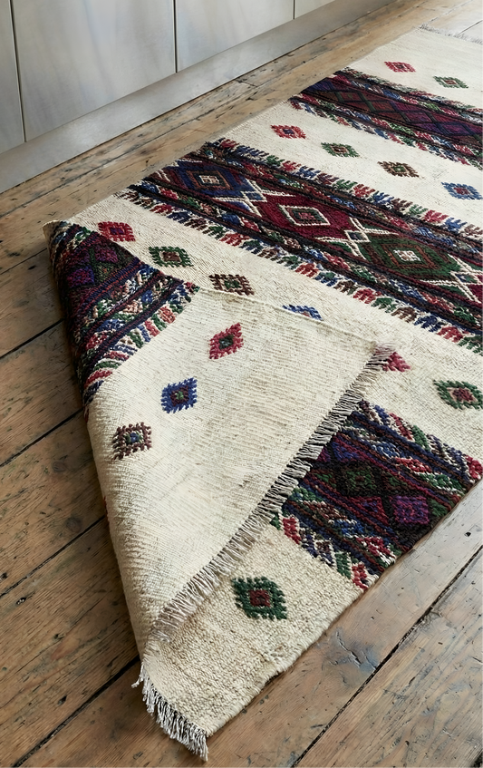 Multicolored patterned Anatolian kilim rug on a wooden floor
