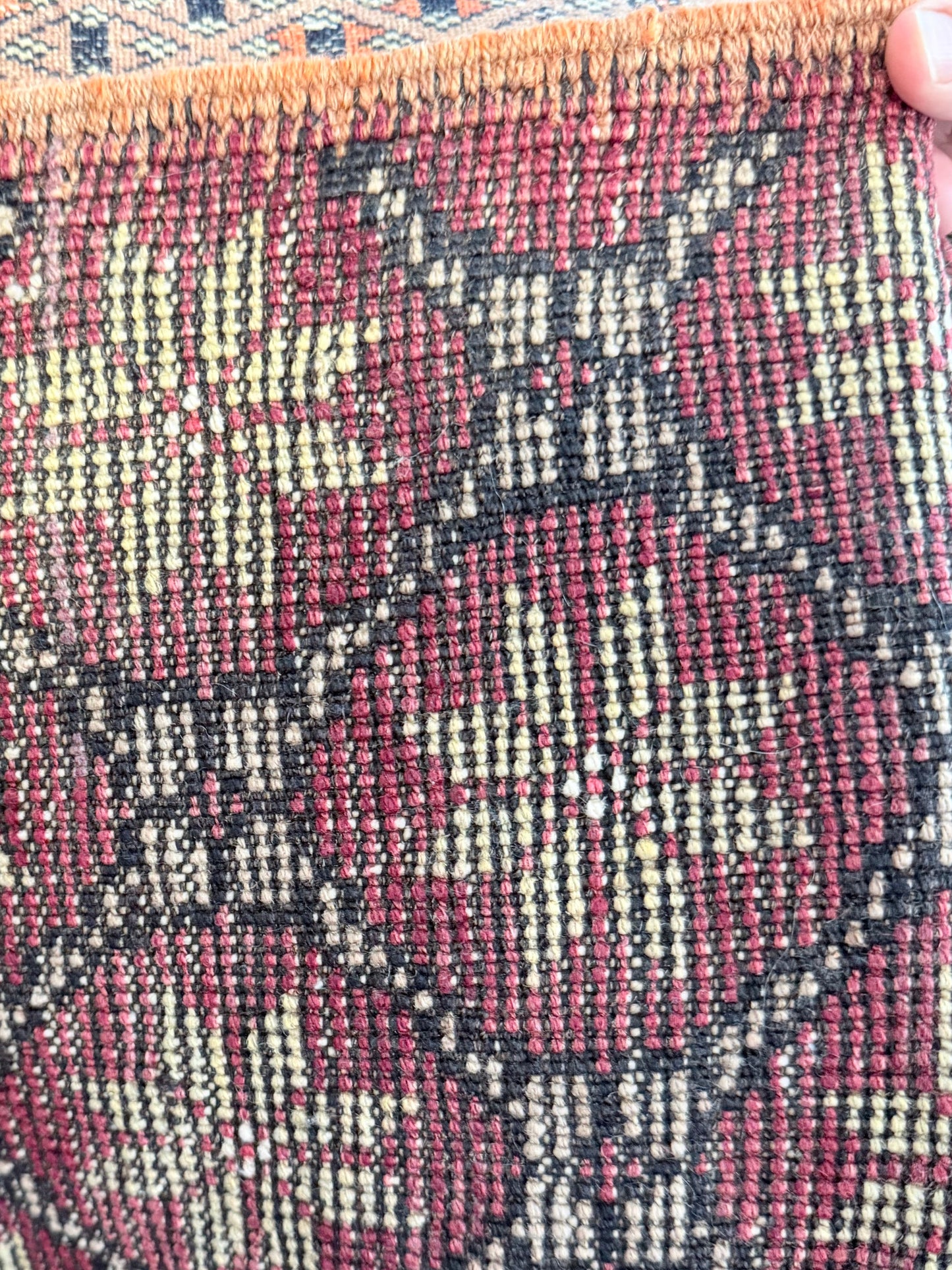 Close-up of a textured fabric with a pattern, held by a hand.