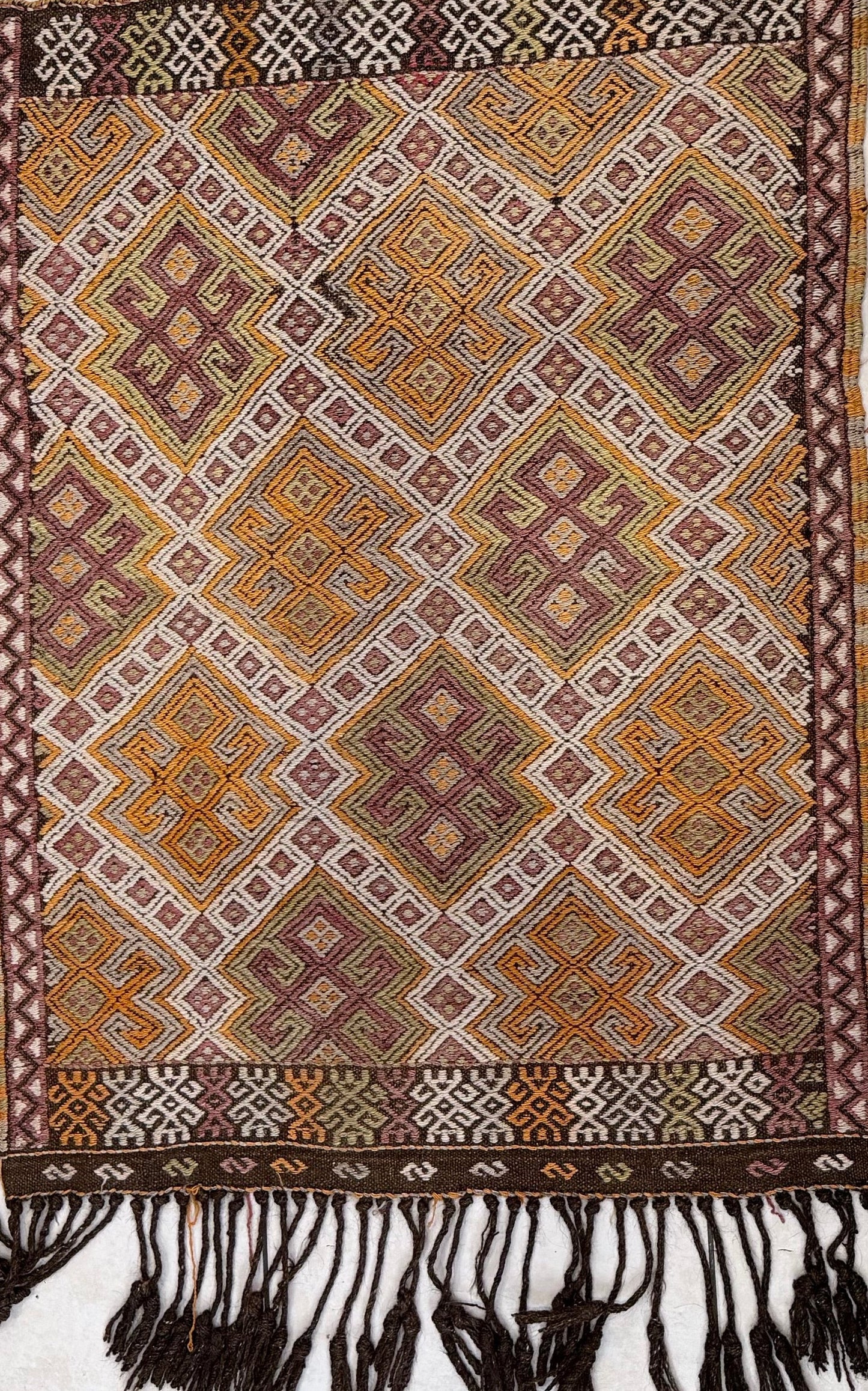 Traditional patterned Anatolian kilim rug with geometric design and fringes at the bottom