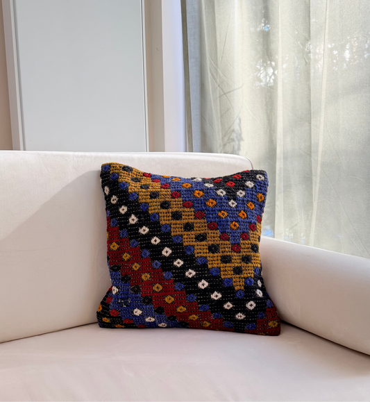 Textured Anatolian "pıtırak" popcorn weave cushion cover with colorful geometric motifs on a charcoal wool base