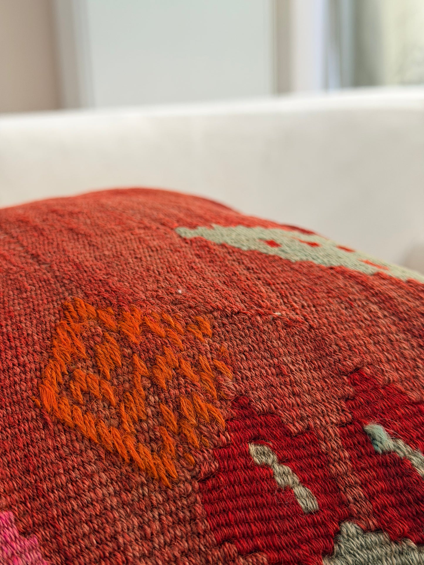 Handwoven rust-toned kilim cushion cover with delicate abstract floral patterns in sage green and dusty pink.