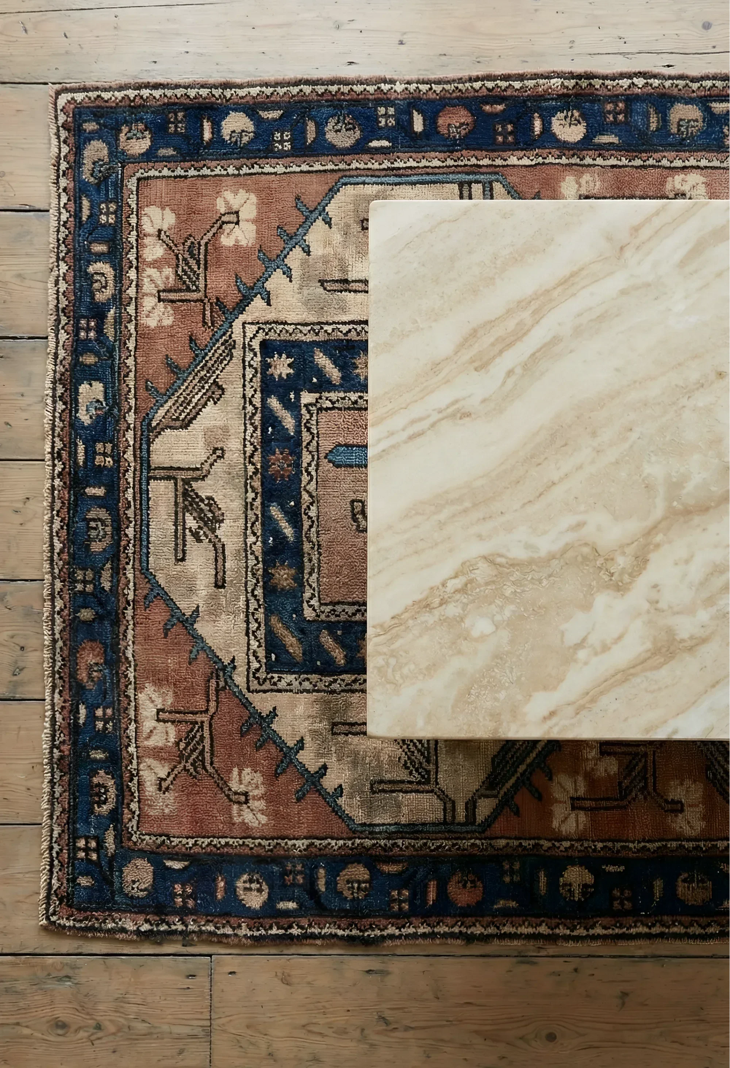 Traditional patterned vintage Anatolian rug on a wooden floor with a close-up marble