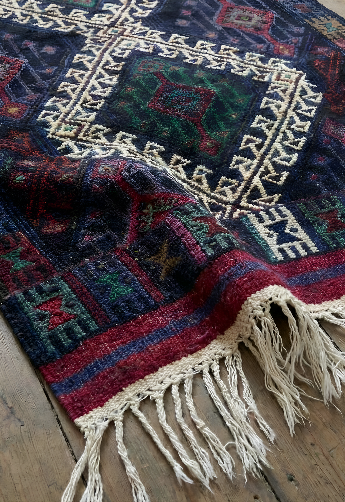 Close-up of a colorful patterned Anatolian kilim rug with fringes on a wooden floor.