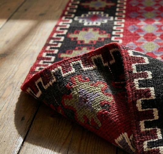 Colorful patterned Anatolian kilim rug on a wooden floor