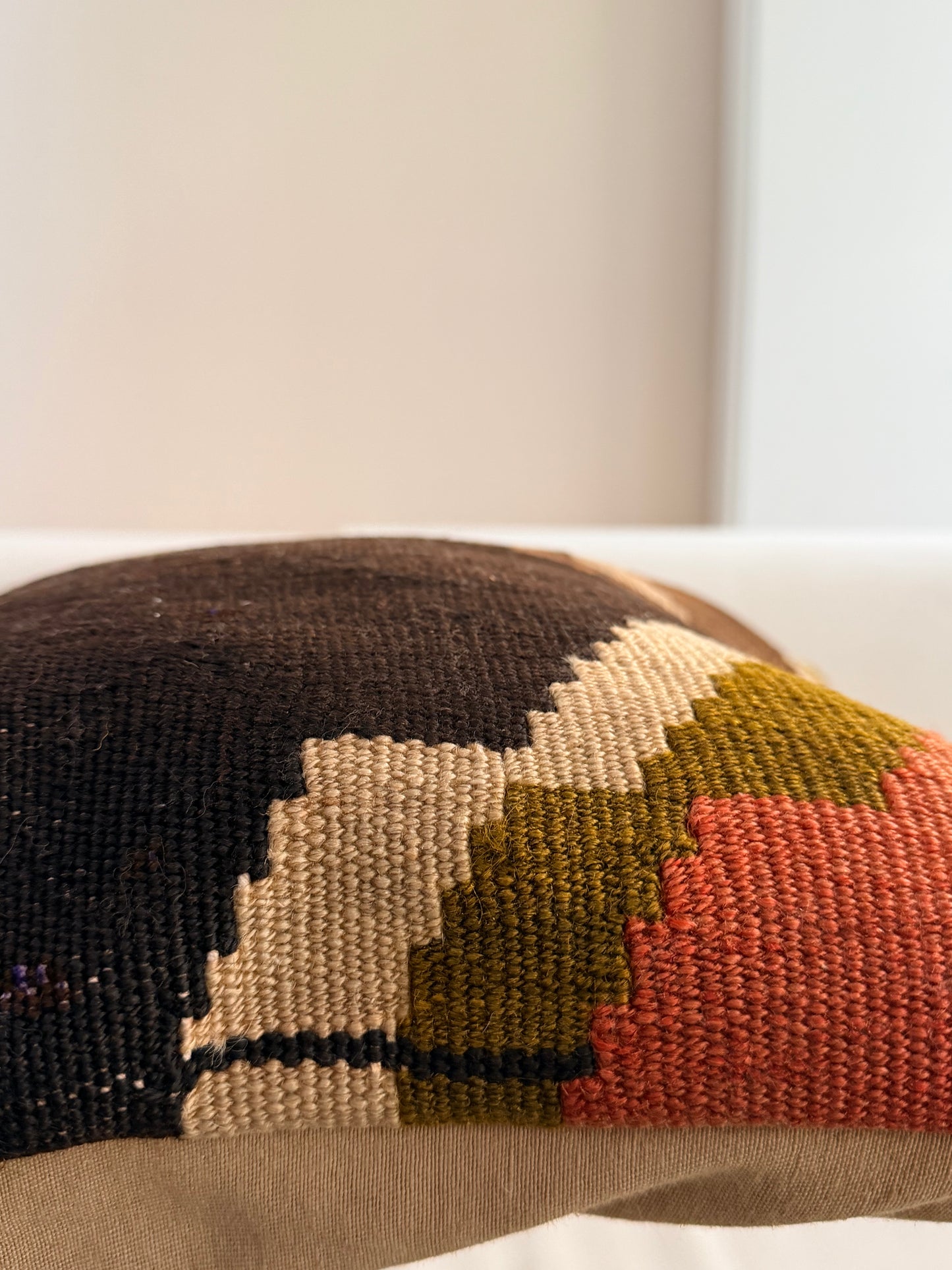 Unique hand-knotted kilim cushion featuring a large abstract geometric pattern in charcoal, moss green, and fuchsia