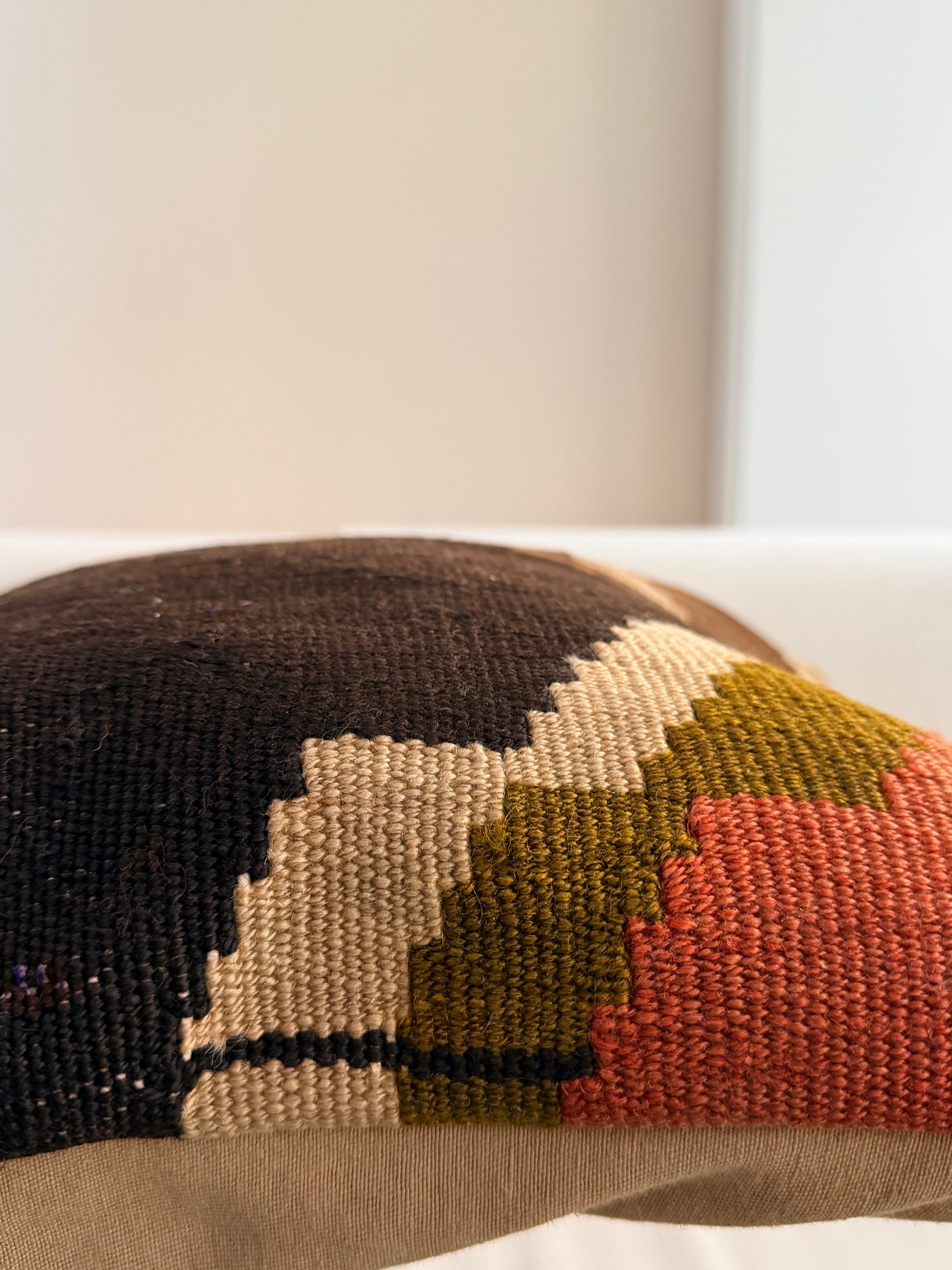 Unique hand-knotted kilim cushion featuring a large abstract geometric pattern in charcoal, moss green, and fuchsia