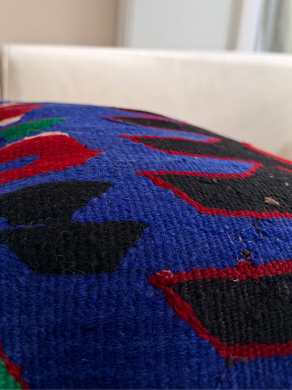 Statement tribal kilim cushion cover with "Ejderha" dragon motifs in bright blue and red on a dark wool weave.