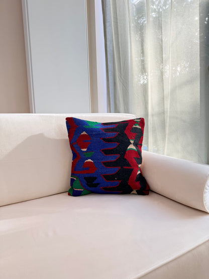 Statement tribal kilim cushion cover with "Ejderha" dragon motifs in bright blue and red on a dark wool weave.