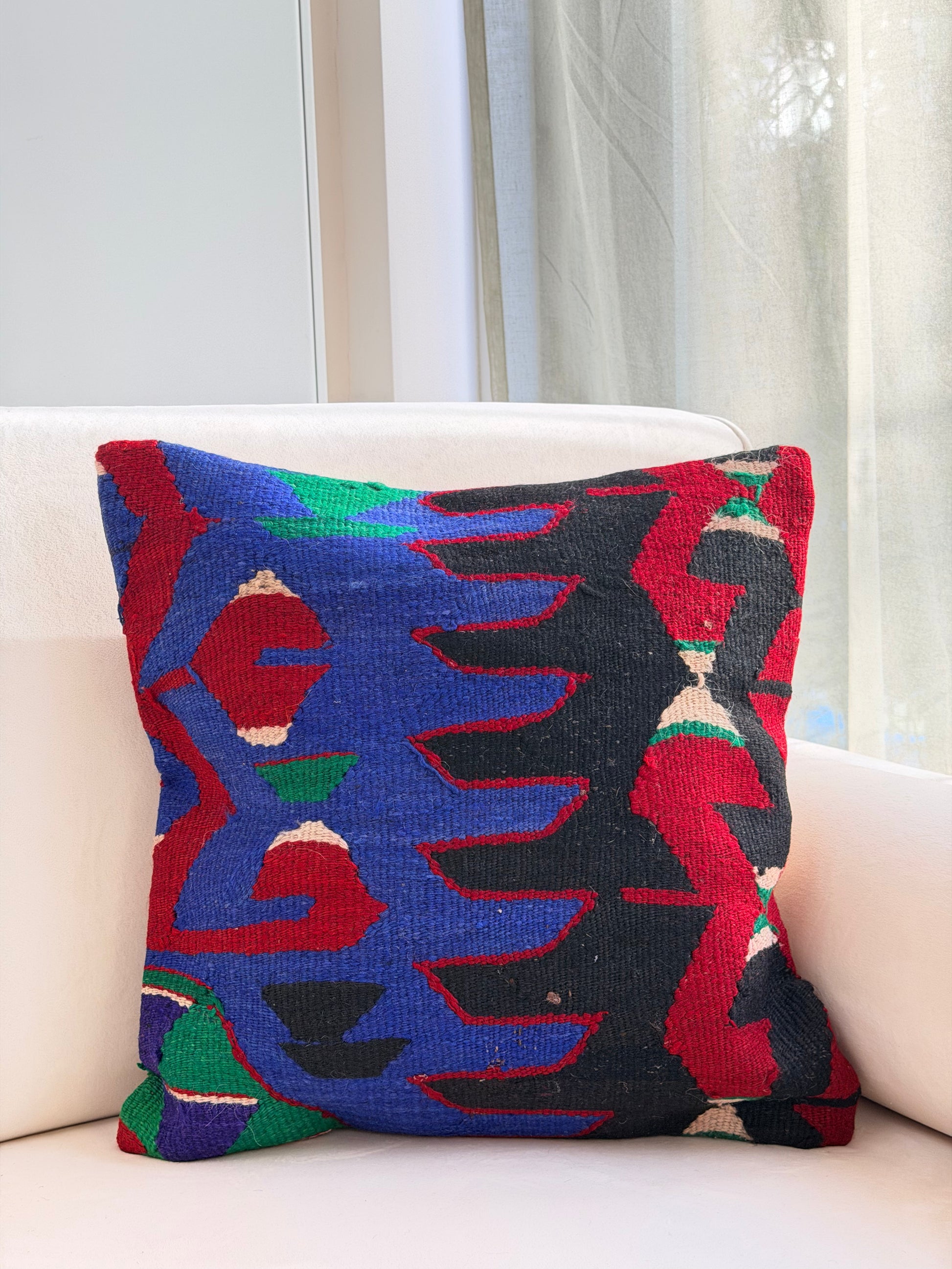 Statement tribal kilim cushion cover with "Ejderha" dragon motifs in bright blue and red on a dark wool weave.