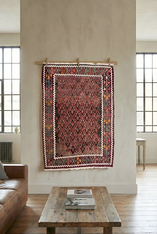 Decorative semi-antique anatolian 100% wool natural dye rug hanging on a wall with a couch and coffee table.