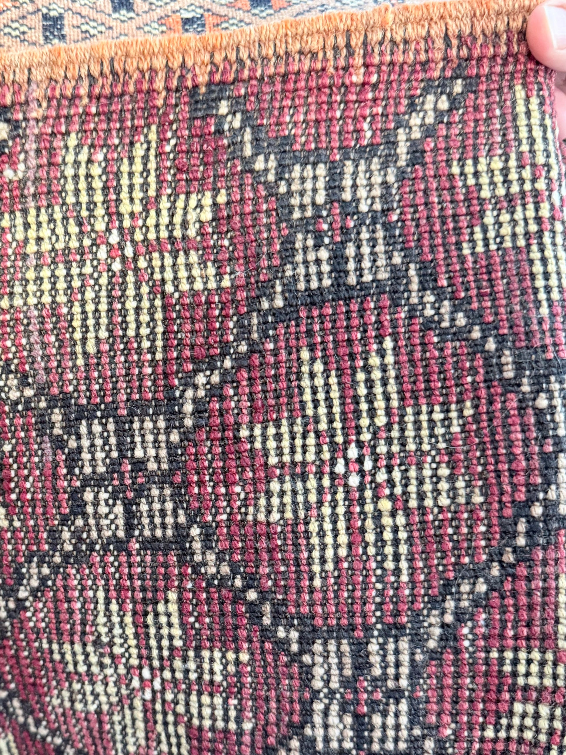 Close-up of a textured fabric with a pattern, held by a hand.