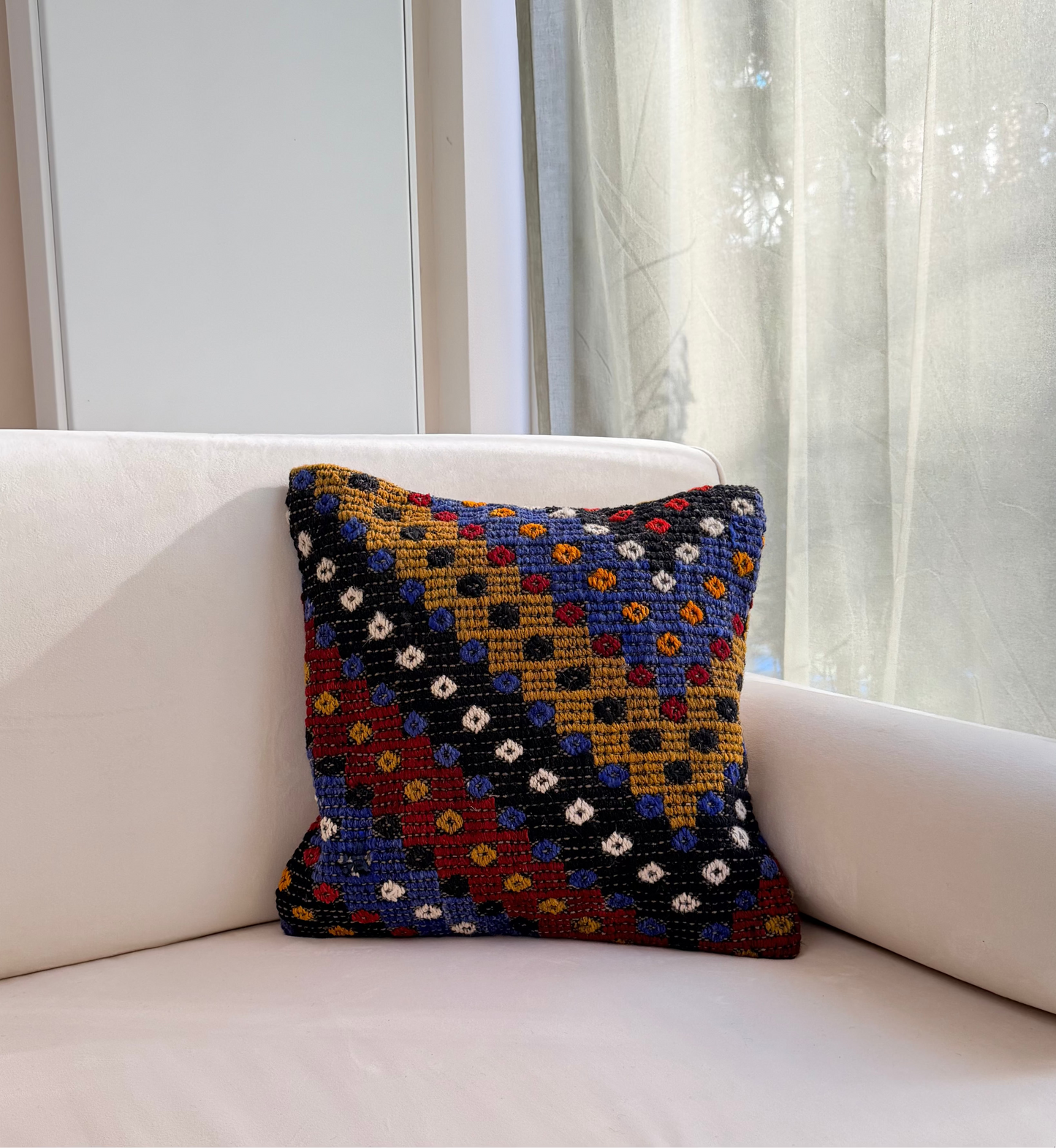 Textured Anatolian "pıtırak" popcorn weave cushion cover with colorful geometric motifs on a charcoal wool base