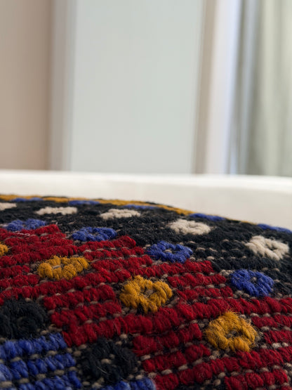 Textured Anatolian "pıtırak" popcorn weave cushion cover with colorful geometric motifs on a charcoal wool base