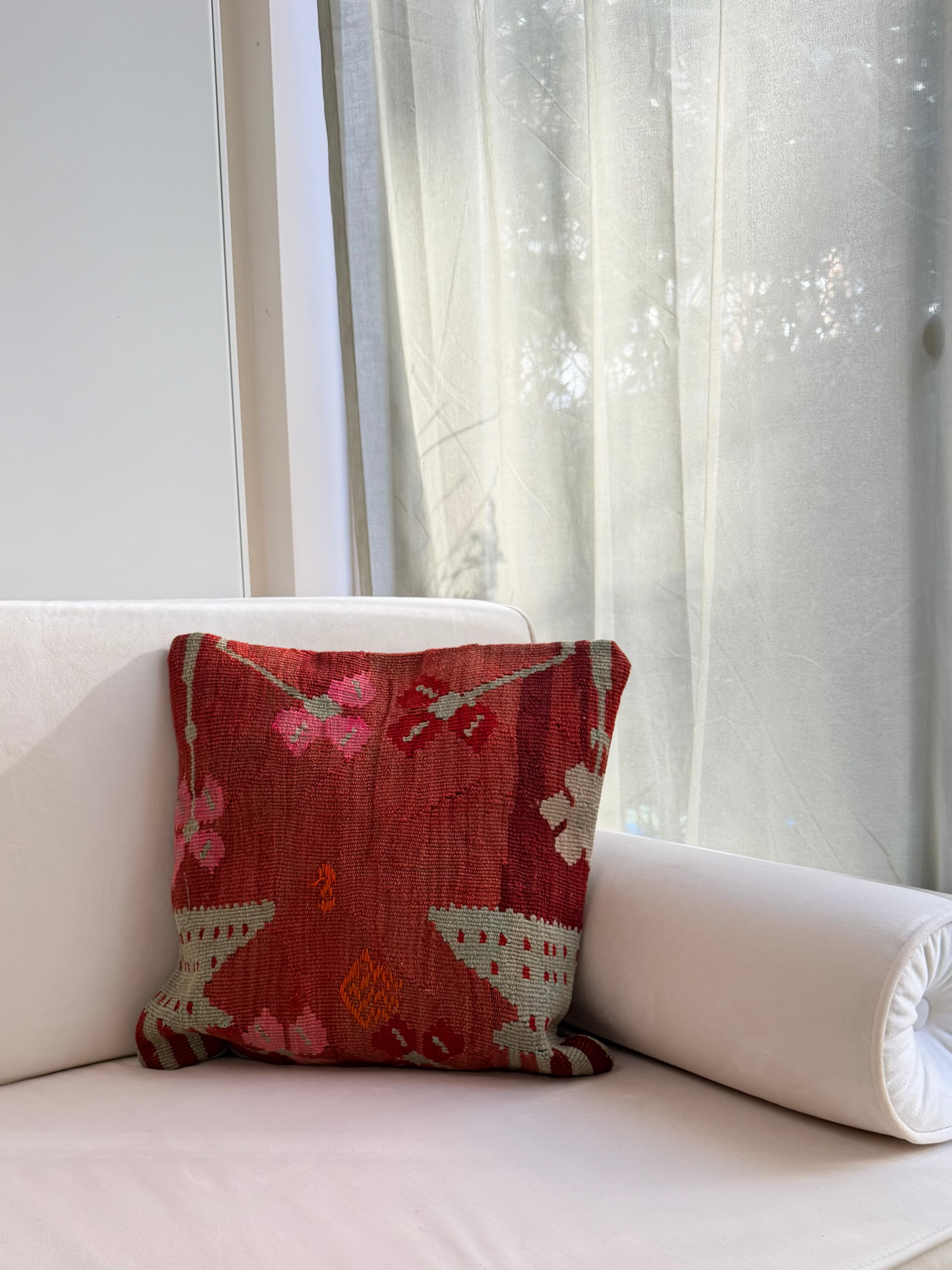 Handwoven rust-toned kilim cushion cover with delicate abstract floral patterns in sage green and dusty pink.
