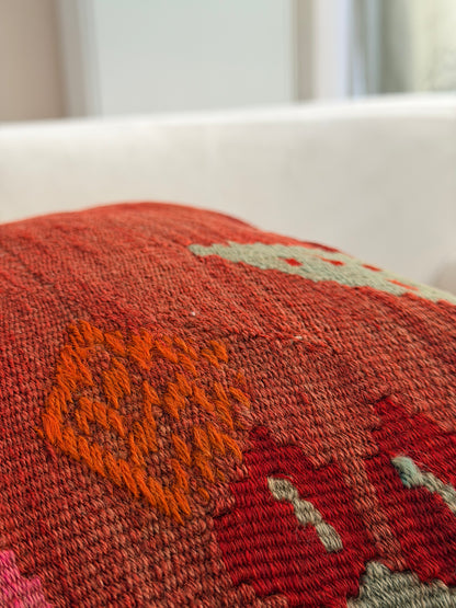 Handwoven rust-toned kilim cushion cover with delicate abstract floral patterns in sage green and dusty pink.