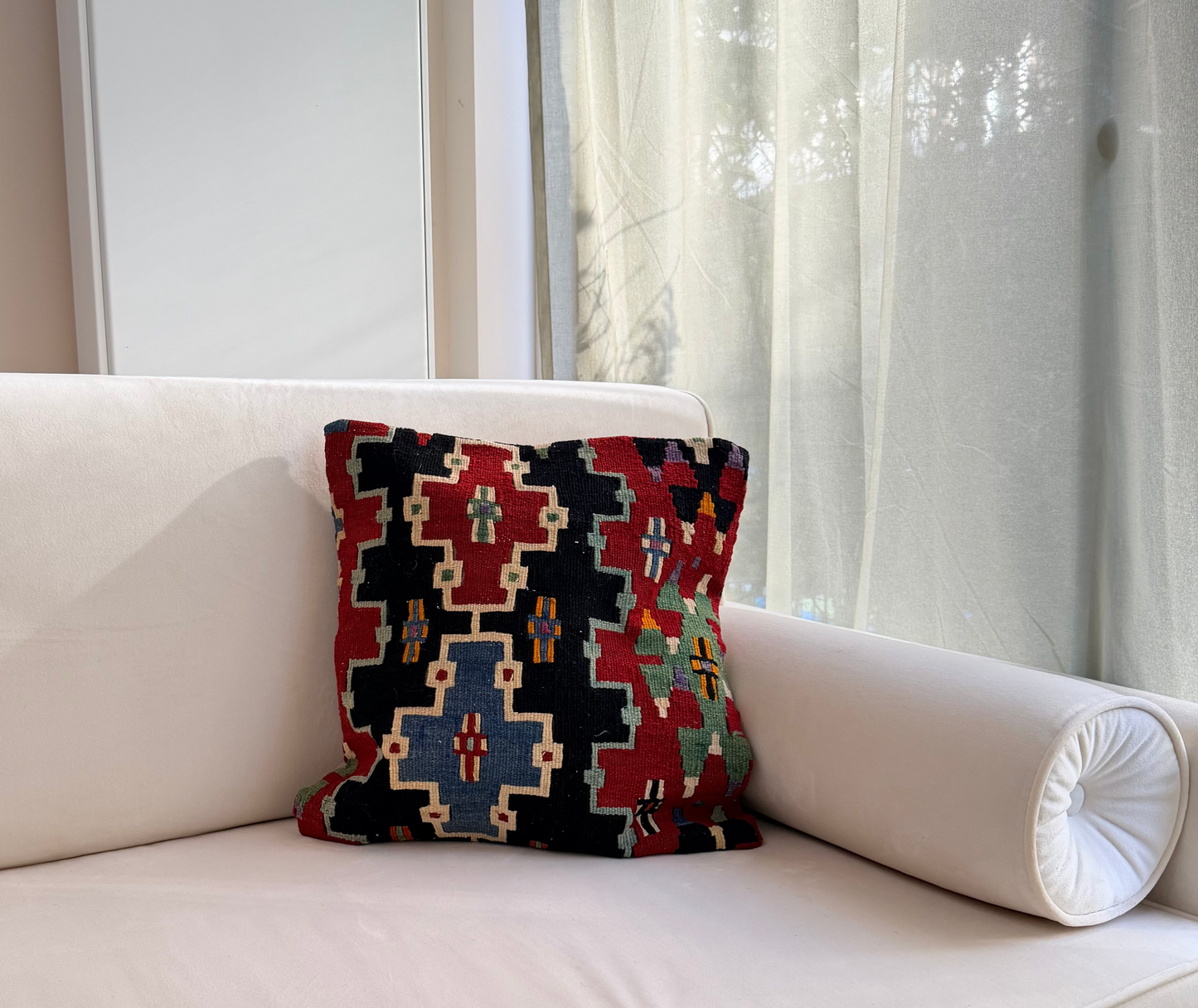 Scandi-Boho kilim cushion cover with a bold stepped geometric design in red, blue, and forest green on dark wool.