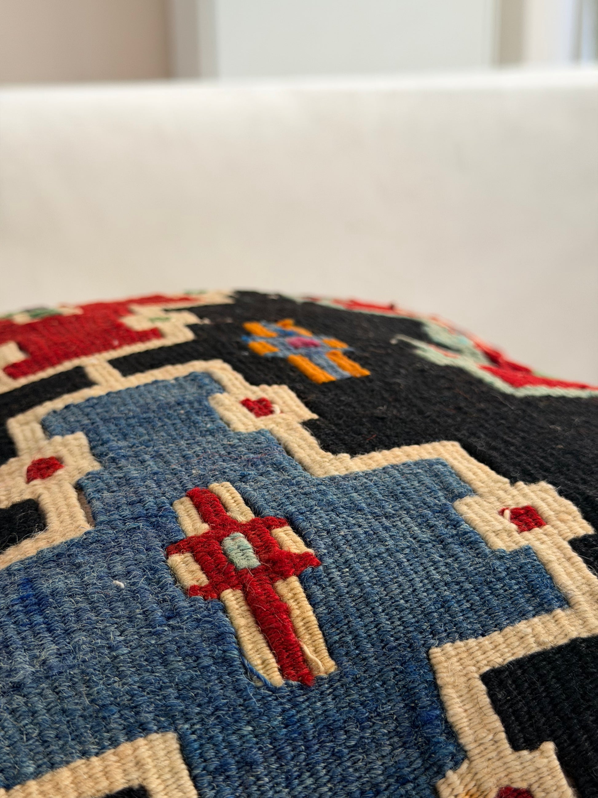 Scandi-Boho kilim cushion cover with a bold stepped geometric design in red, blue, and forest green on dark wool.