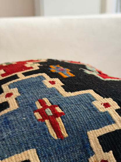 Scandi-Boho kilim cushion cover with a bold stepped geometric design in red, blue, and forest green on dark wool.