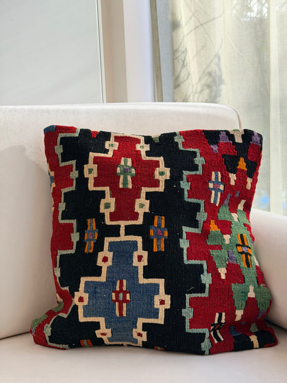 Scandi-Boho kilim cushion cover with a bold stepped geometric design in red, blue, and forest green on dark wool.