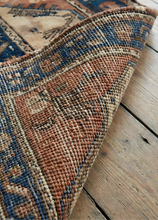 Close-up of an antique Anatolian rug with intricate patterns on a wooden floor