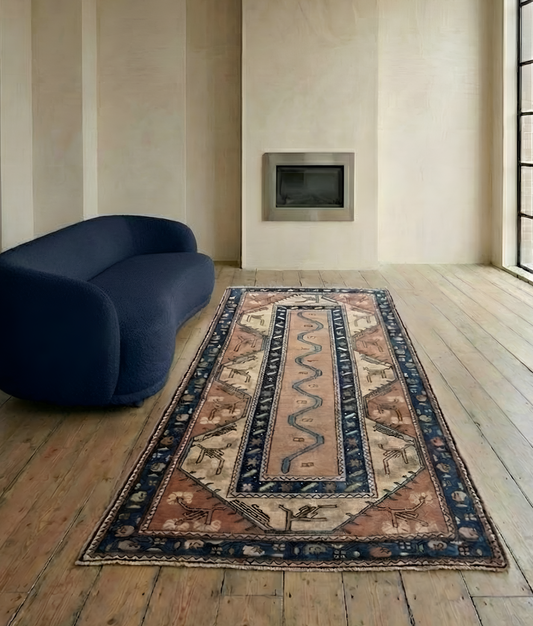 Blue sofa, with a patterned semi- antique Anatolian rug with intricate patterns on a wooden floor. 