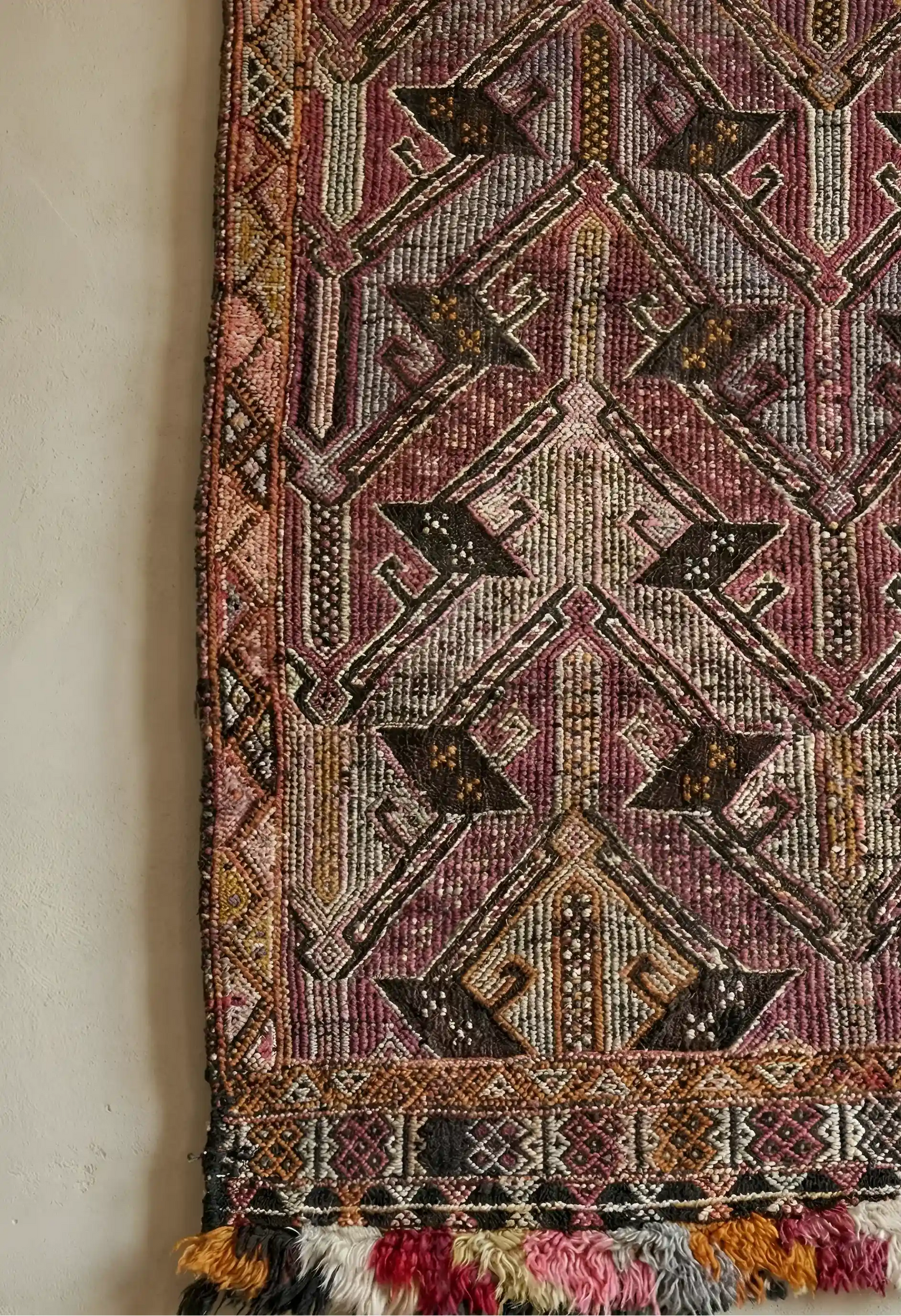 Anatolian rug with intricate patterns and tassels on a plain background