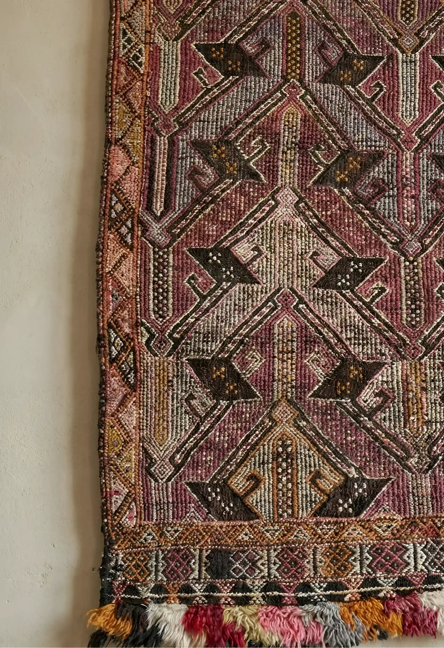 Anatolian rug with intricate patterns and tassels on a plain background
