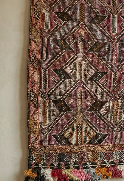 Anatolian rug with intricate patterns and tassels on a plain background