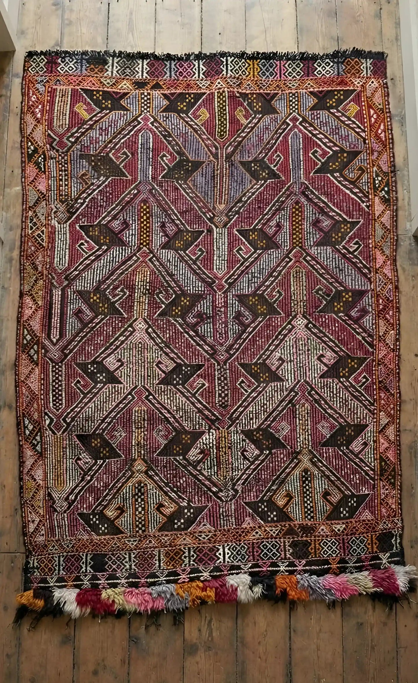 Anatolian rug with intricate patterns on a wooden floor