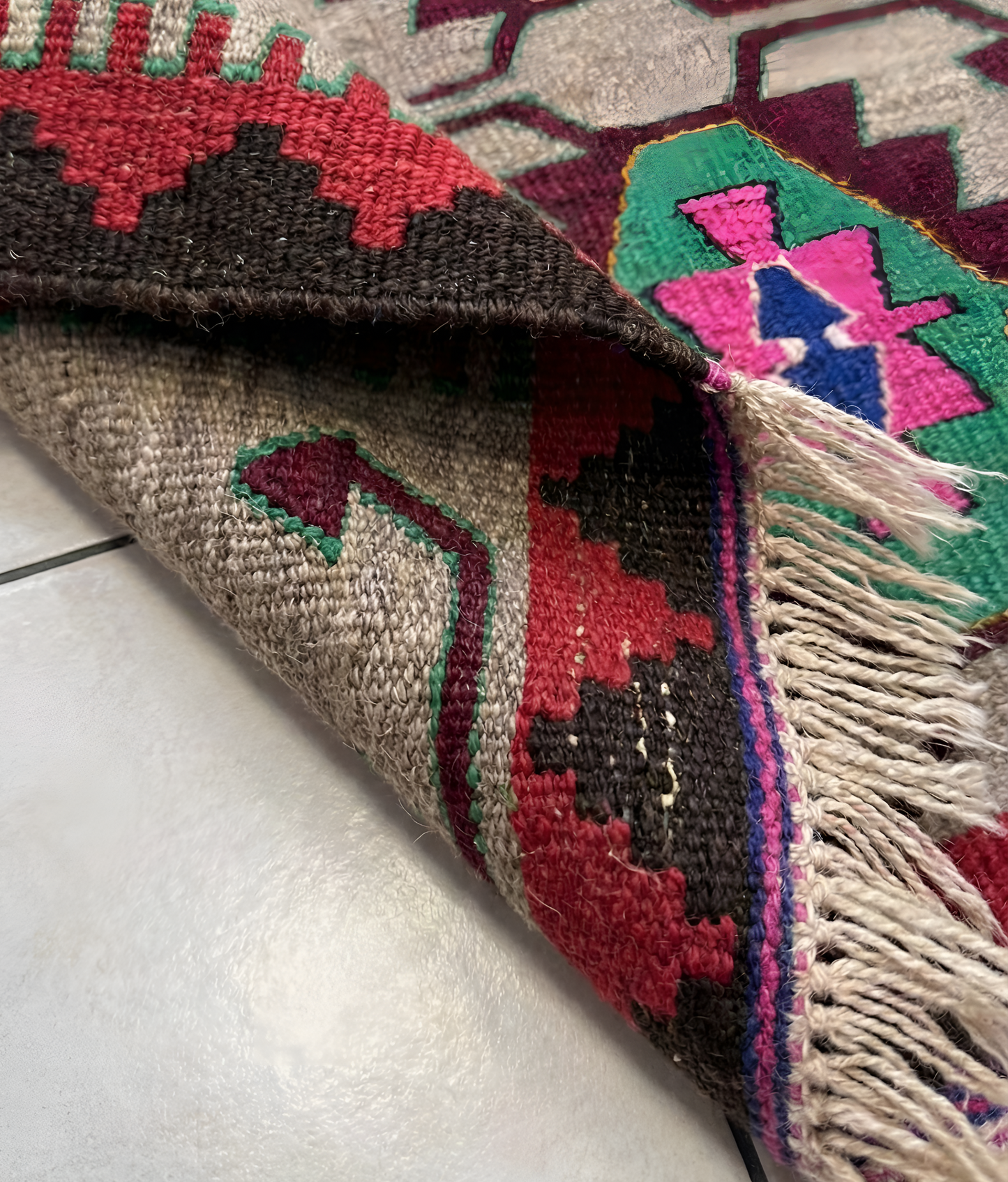 Close-up of a colorful wool anatolian woven rug with geometric patterns on a white surface.