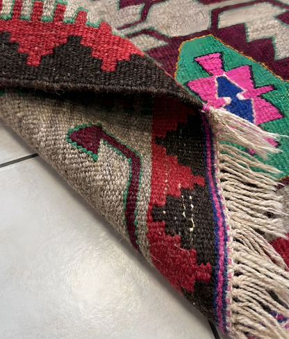 Close-up of a colorful wool anatolian woven rug with geometric patterns on a white surface.