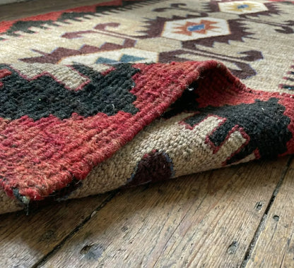 Close-up of a patterned Anatolian kilim rug on a wooden floor