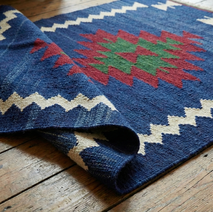 Blue patterned Anatolian kilim rug with red and green center on a wooden floor
