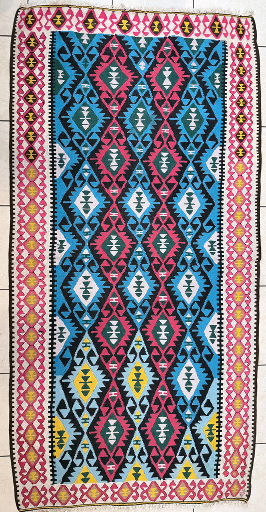 A vibrant, vintage Turkish Kilim runner featuring a geometric diamond pattern in turquoise, pink, and yellow