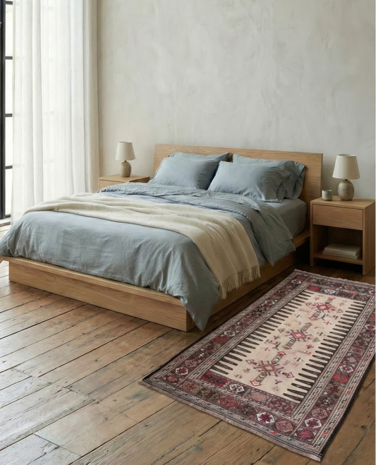 Bedroom with wooden bed, and flatwoven wool vintage rug on wooden floor