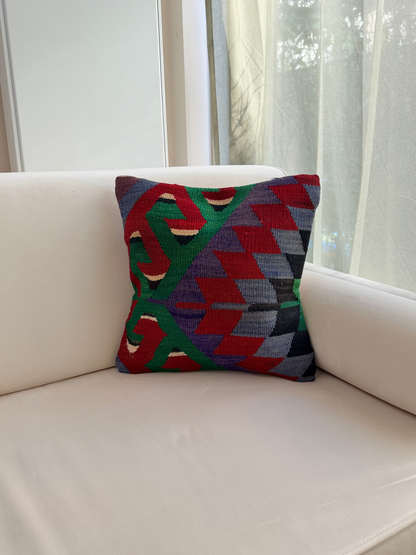 Authentic wool cushion cover with intricate geometric patterns in emerald green, crimson red, and muted violet