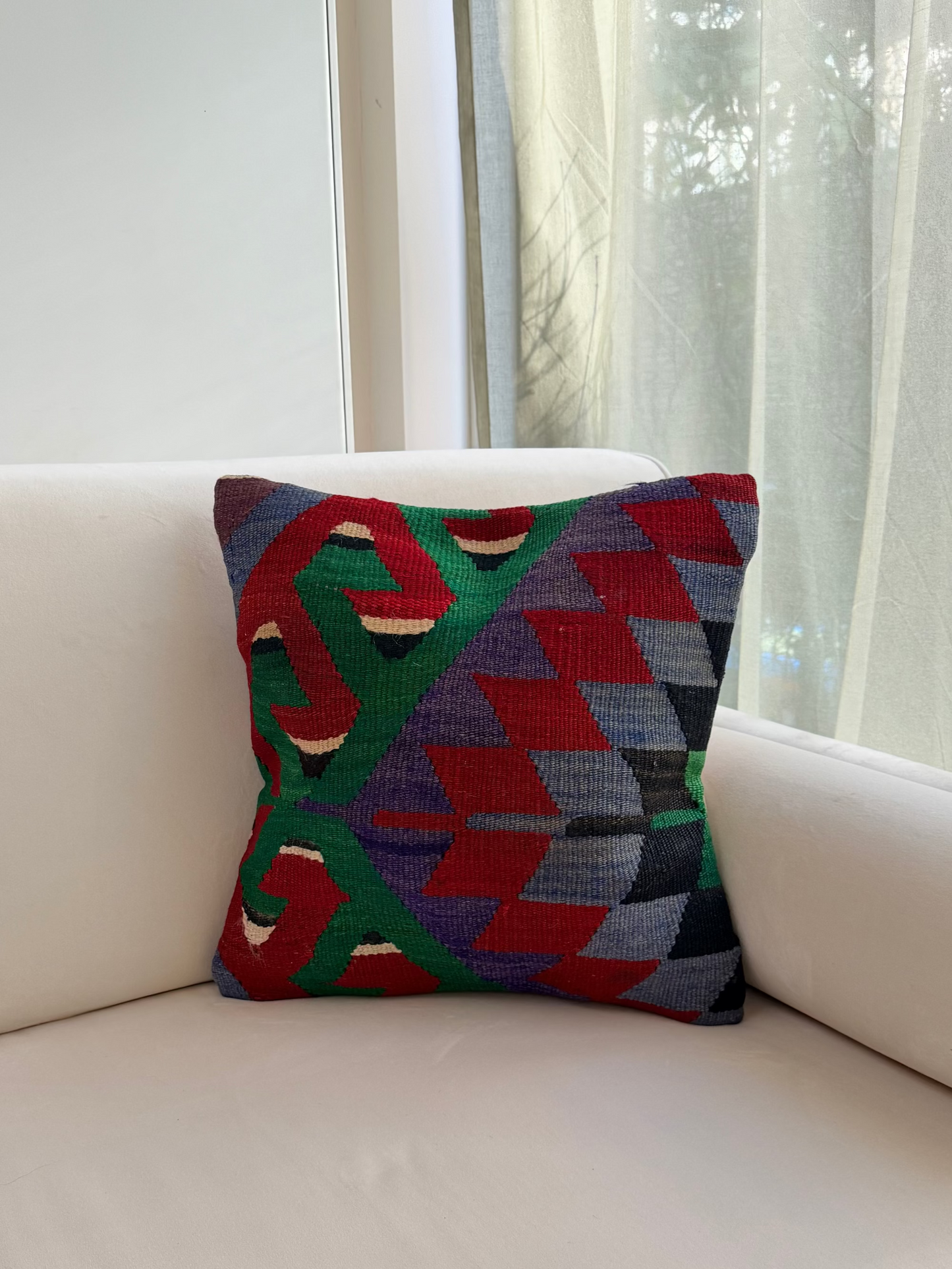 Authentic wool cushion cover with intricate geometric patterns in emerald green, crimson red, and muted violet